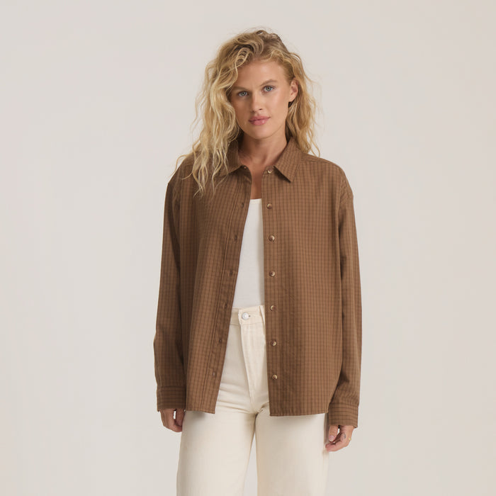 Brown ribbed button-up shirt with long sleeves worn over white top by model with wavy blonde hair