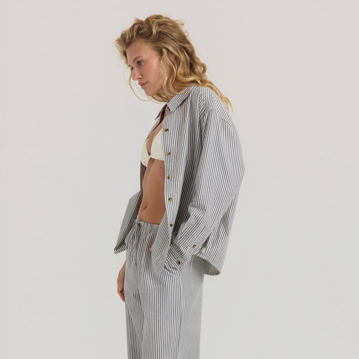 Blond model in a fashion photo shoot, adjusting a button on a trendy outdoor adventure outfit.