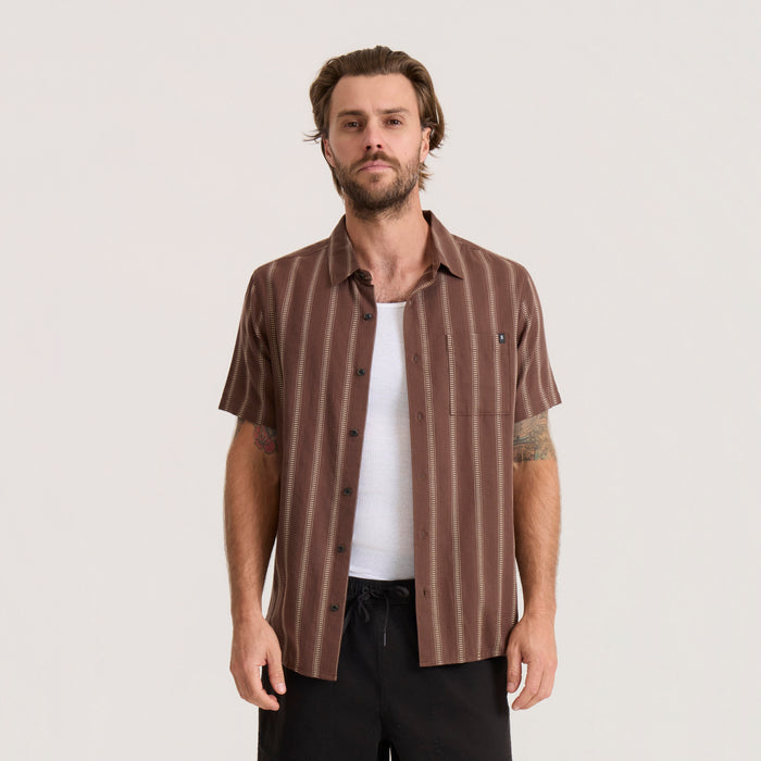 Brown striped short-sleeve button-up shirt with white vertical dotted stripes worn by man over white tank top