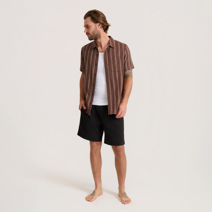 Brown striped short-sleeve button-up shirt worn open over white undershirt on model with black shorts