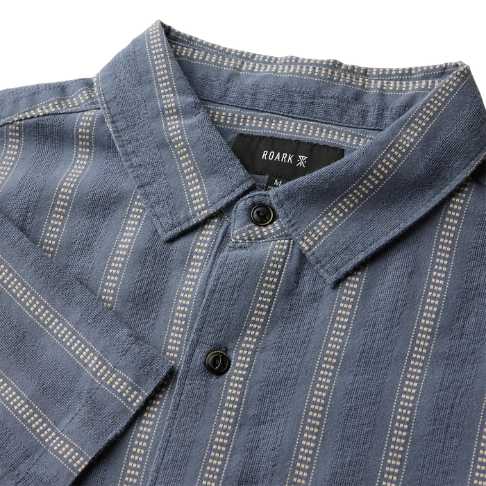 Close-up of a stylish silver button on Roark outdoor apparel, emphasizing rugged and functional design.