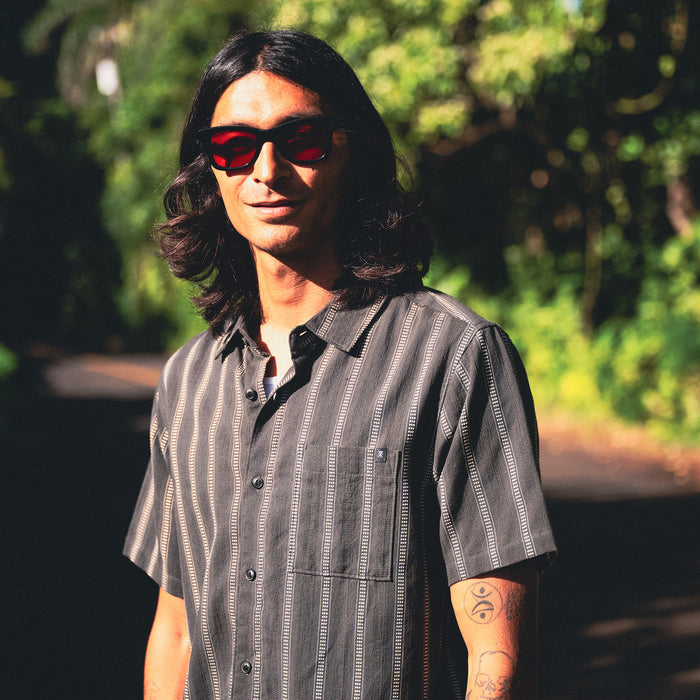 Stylish adventurer wearing sunglasses pairing with the Crosswinds Button Up Shirt, perfect for outdoor travel and exploration.
