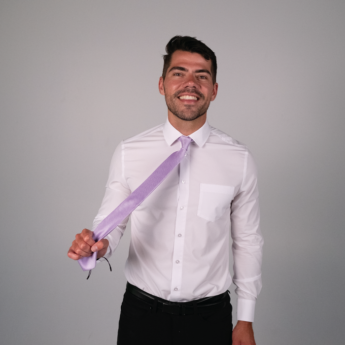 A man wearing a solid purple tie on a white dress shirt.