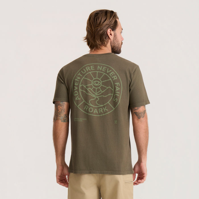 Military green Division Premium Tee worn by man showing back graphic with circular adventure-themed design and text