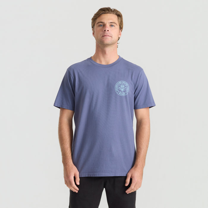 Man wearing Roark active shirt paired with denim jeans in an outdoor travel setting, showcasing a blend of adventure and style.