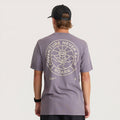 Gray short-sleeve t-shirt with circular back graphic reading "Adventure Never Fails Roark" in tan, worn by model with black cap
