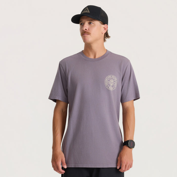 Man wearing dusty purple Division Premium Tee with circular chest logo, paired with black cap, front-facing studio shot