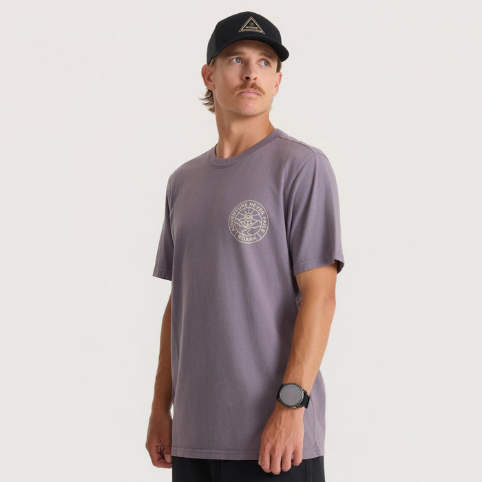 Man wearing charcoal gray Division Premium Tee with circular logo on chest, black cap, paired with black pants in lifestyle shot