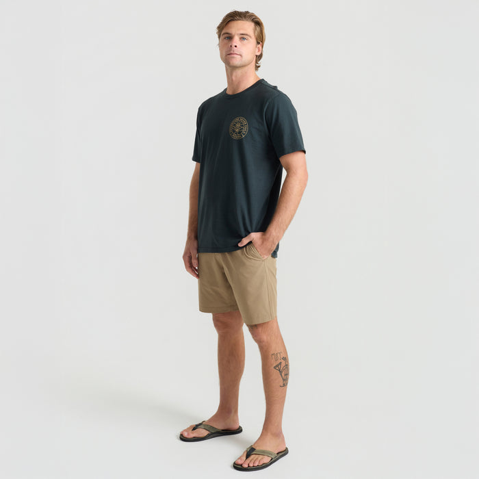 Man wearing versatile Roark boardshorts, perfect for exploring rugged terrains or surfing, highlighting functionality and comfort in an outdoor setting.