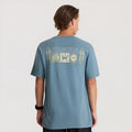 Slate blue short sleeve tee with Roark graphic print on back, displayed on male model from behind against neutral background