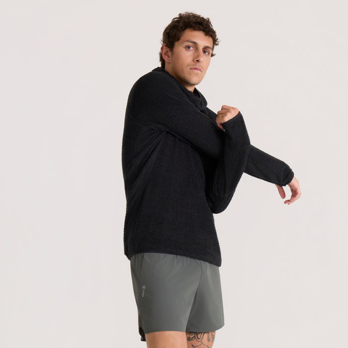 Black Evolve hoodie with ribbed texture on male model wearing gray shorts, shown from side angle