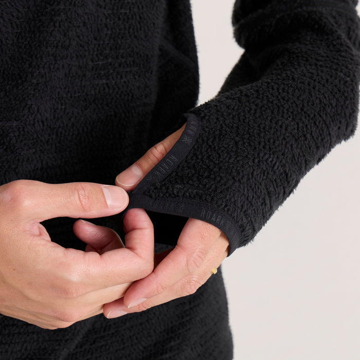 Black Evolve hoodie shown close-up on model, displaying textured fabric and ribbed cuff detail