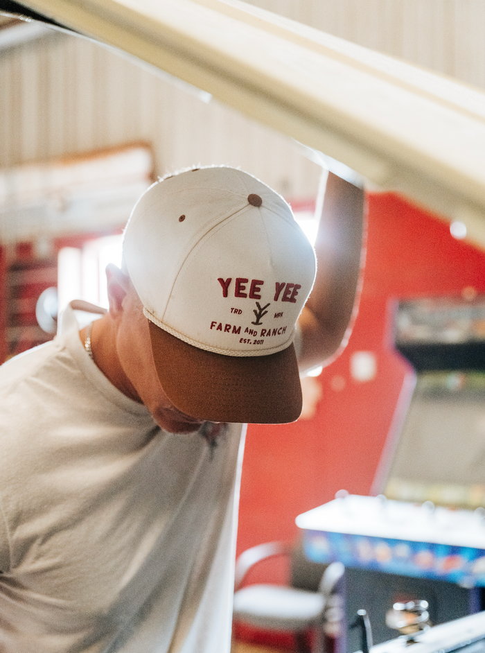 Person wearing a cap with 'Yee Yee' text in an indoor setting