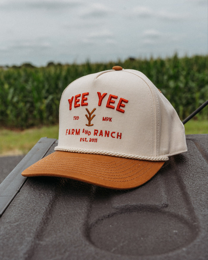 Cap with 'Yee Yee Farm and Ranch' text on a truck bed with a cornfield background