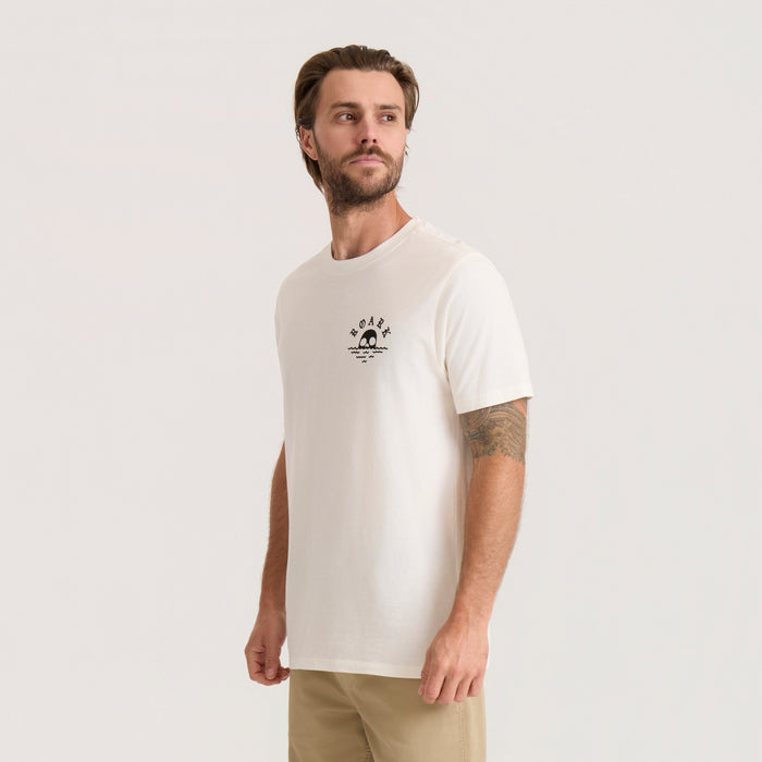 Off white short sleeve tee with small Roark logo graphic on chest, worn by man on neutral background