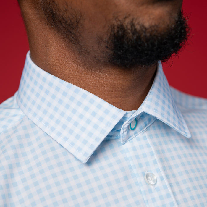 Man wearing pale blue shirt with white gingham. Top button has blue ring.