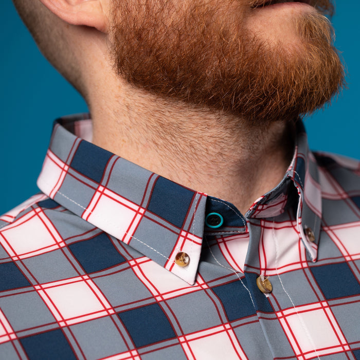 Man wearing white and Navy shirt w/ Red Accents. Top button has blue ring.