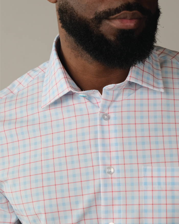 Man wearing white with Red and Blue Windowpane shirt. Top button has blue ring.