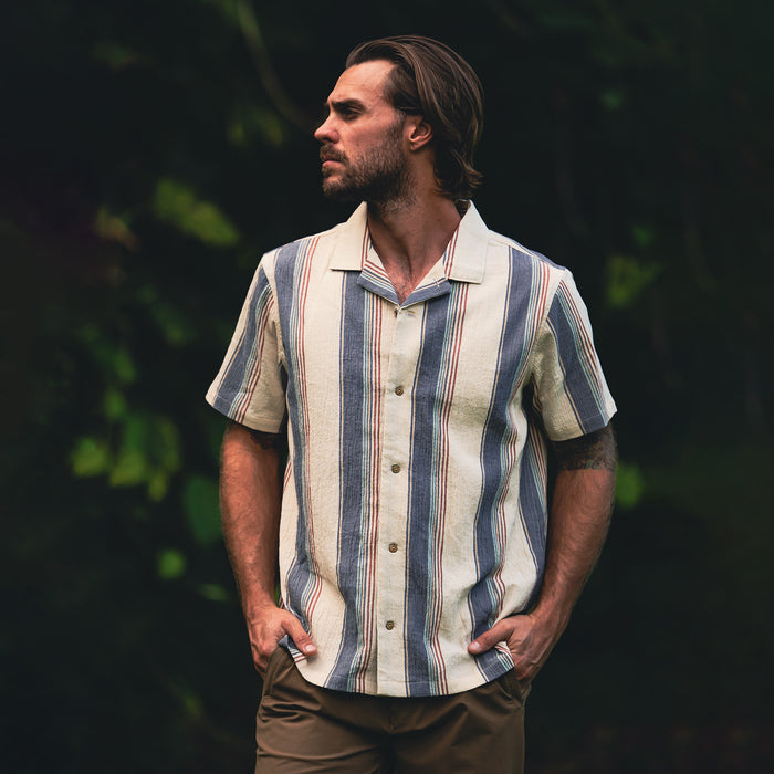 Gonzo short sleeve button up shirt in ivory with blue and red vertical stripes, worn by man in outdoor setting