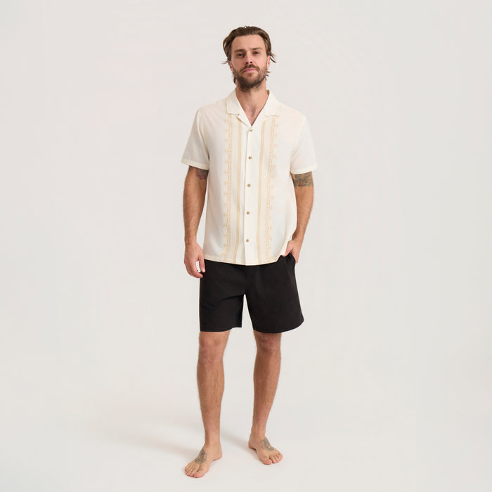 Cream short sleeve button up shirt with vertical embroidery worn by man standing against neutral background in full body shot