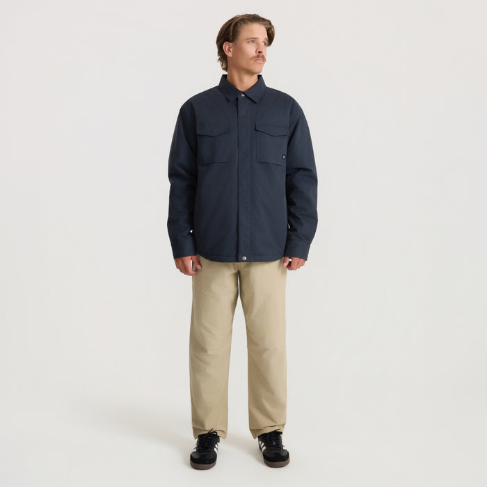 Man wearing deep navy Hebrides 10k jacket with chest pockets and khaki pants, standing against neutral background