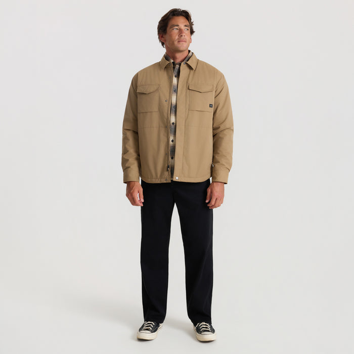 Khaki Hebrides 10k jacket worn by man with black pants and canvas sneakers in full-length front view