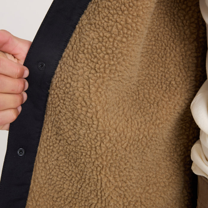 Hebrides 2.0 Sherpa Jacket in black with tan sherpa fleece lining, detail shot showing textured interior and button closure on model