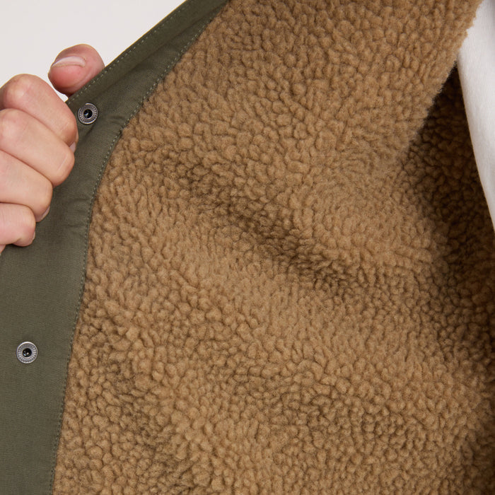 Hebrides 2.0 Sherpa Jacket in military green with tan fleece interior, detail of snapped edge and texture held by hand