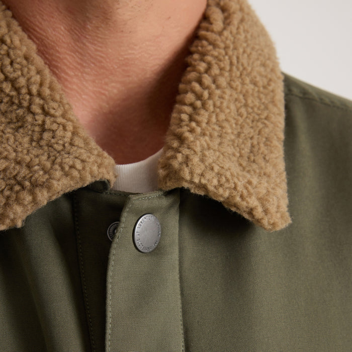 Hebrides 2.0 Sherpa Jacket in military green with tan sherpa collar, worn with white shirt, detail view of button and neckline