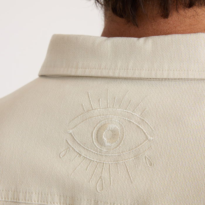 Cream ribbed Hebrides 2.0 jacket worn by model, showing embroidered eye detail on back panel and fold-over collar