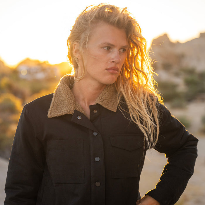Black Hebrides Sherpa Jacket with cream fleece collar worn by model outdoors at golden hour sunset
