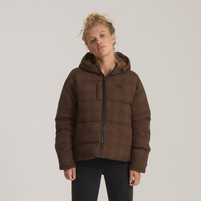 Brown quilted puffer jacket with hood on model wearing black pants, front view