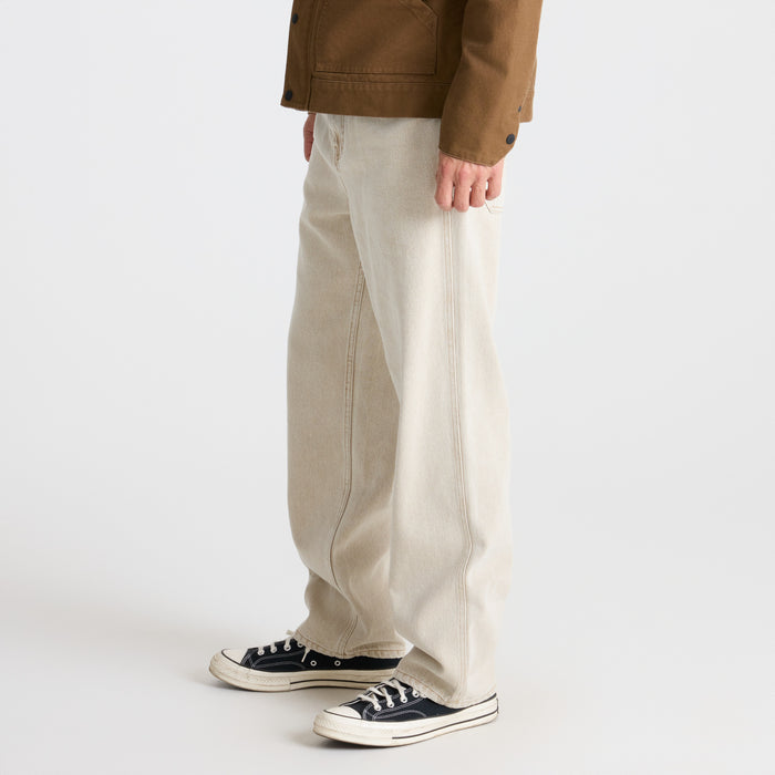 Close-up of khaki pants detailing with leather and stitch accents on pocket and button, ideal for adventure and travel.