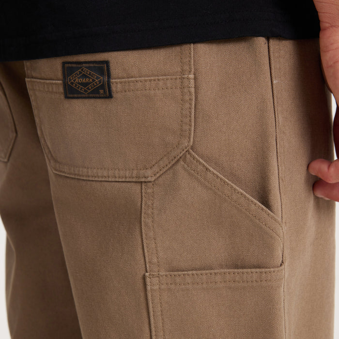 Khaki HWY 1 utility denim with cargo pockets and Roark woven label on model, detail view of thigh and pocket construction