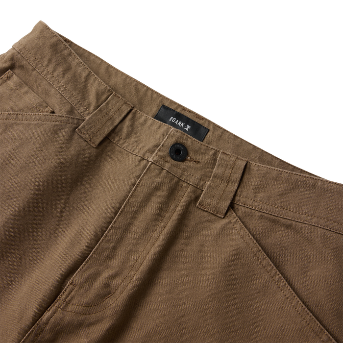 Khaki HWY 1 utility denim jeans with black button and front pocket detail, angled flat lay view showing waistband and Roark label