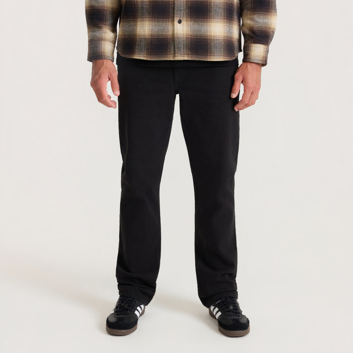 Man wearing black HWY 128 five-pocket denim jeans with plaid shirt, front view on neutral background