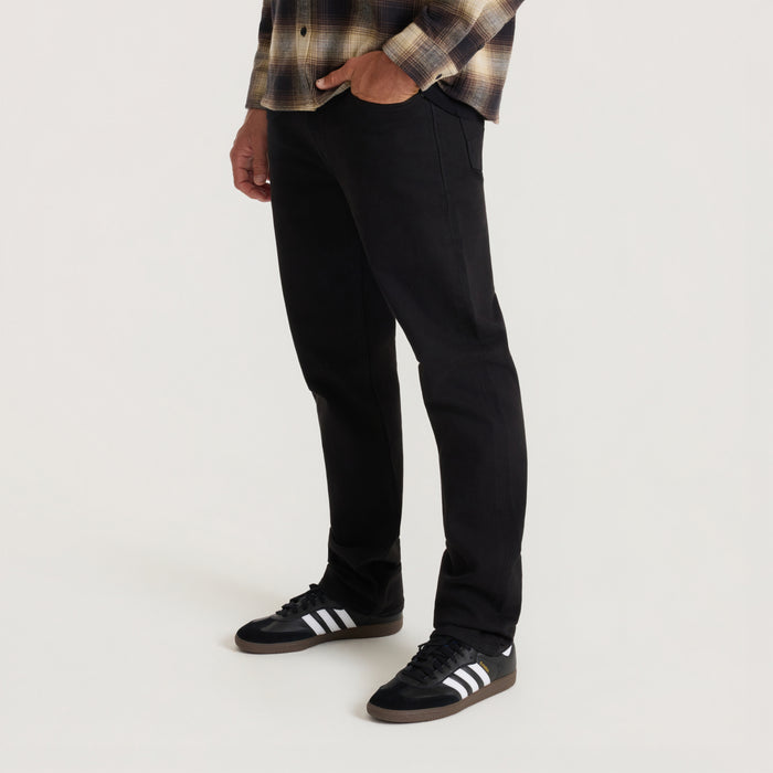 Black HWY 128 five-pocket denim jeans on model styled with plaid shirt and black sneakers with white stripes