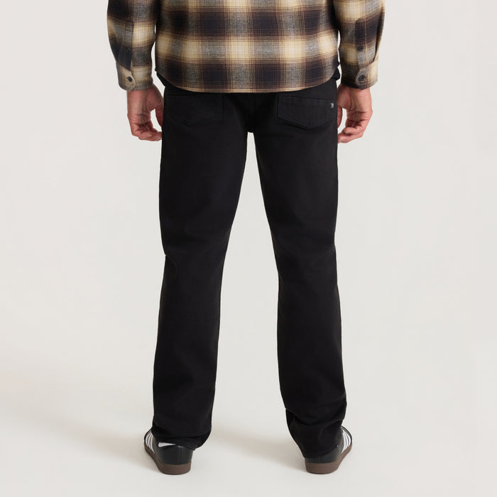 Man wearing black HWY 128 five-pocket broken twill denim jeans, shown from behind with plaid shirt visible at top