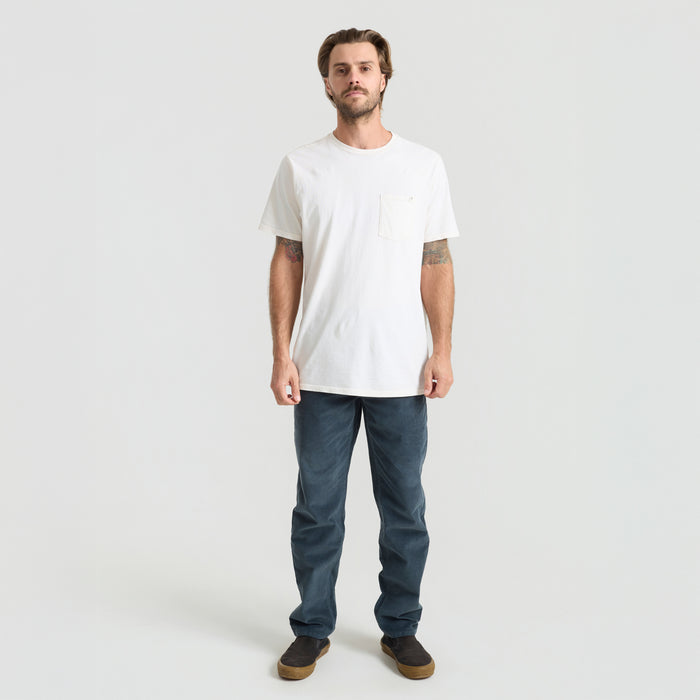 Man standing in rugged outdoor setting, showcasing the durable denim with focus on sleeves, waist design, and pockets