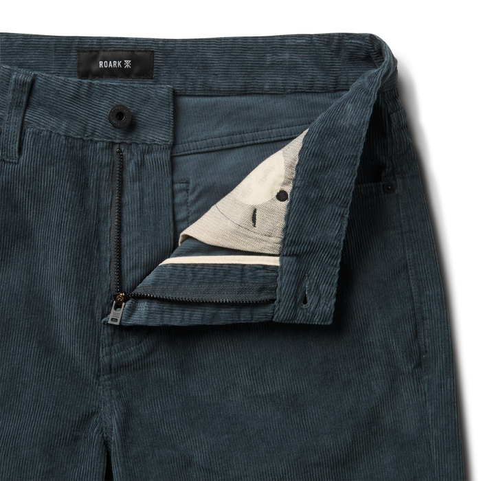 Close-up of rugged denim with detailed stitching, button, and pocket design, embodying Roark's adventure-ready apparel style.