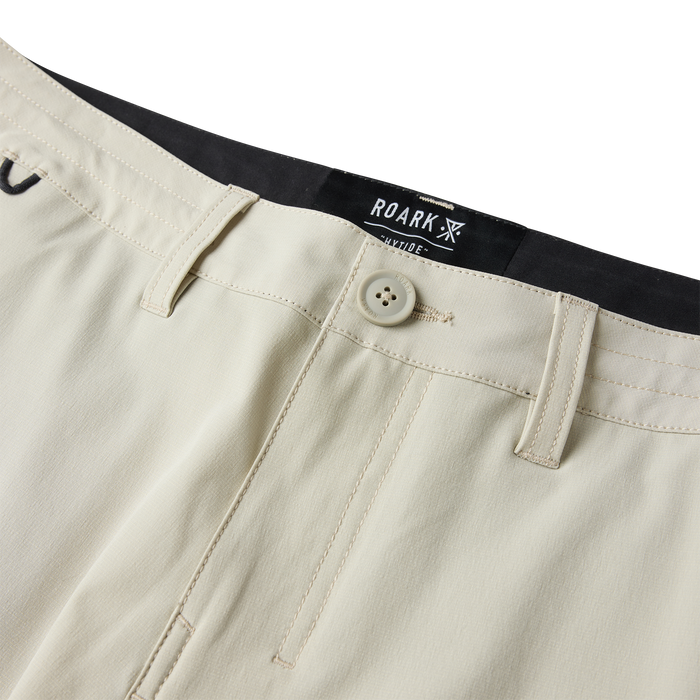 Roark Hytide Hybrid Shorts in sand with black waistband label, four-hole button, and flat lay detail view