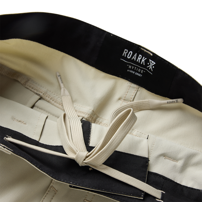 Roark Hytide Hybrid Shorts in sand with black waistband and cream drawstring, flat lay detail shot