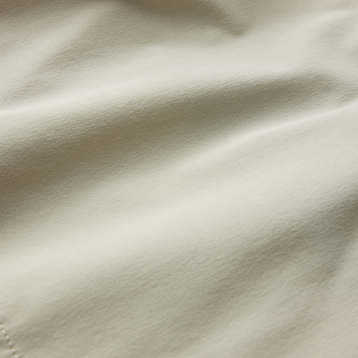 Cream-colored Hytide Hybrid Shorts in sand fabric showing close-up texture and weave detail with natural draping shadows