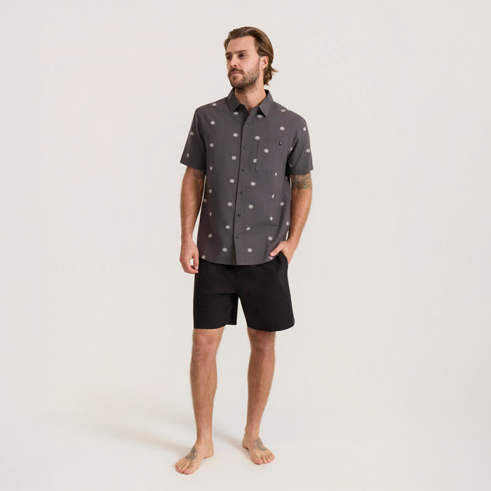 Charcoal short sleeve button up shirt with white floral print worn by man on model, styled with black shorts