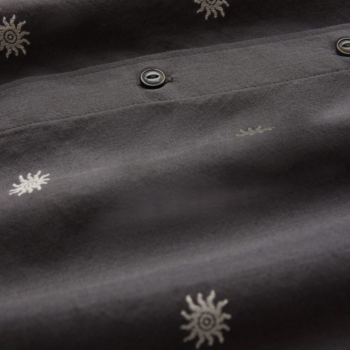 Charcoal short sleeve button up shirt with embroidered sun motifs and metal eyelets, detail shot of fabric and buttons