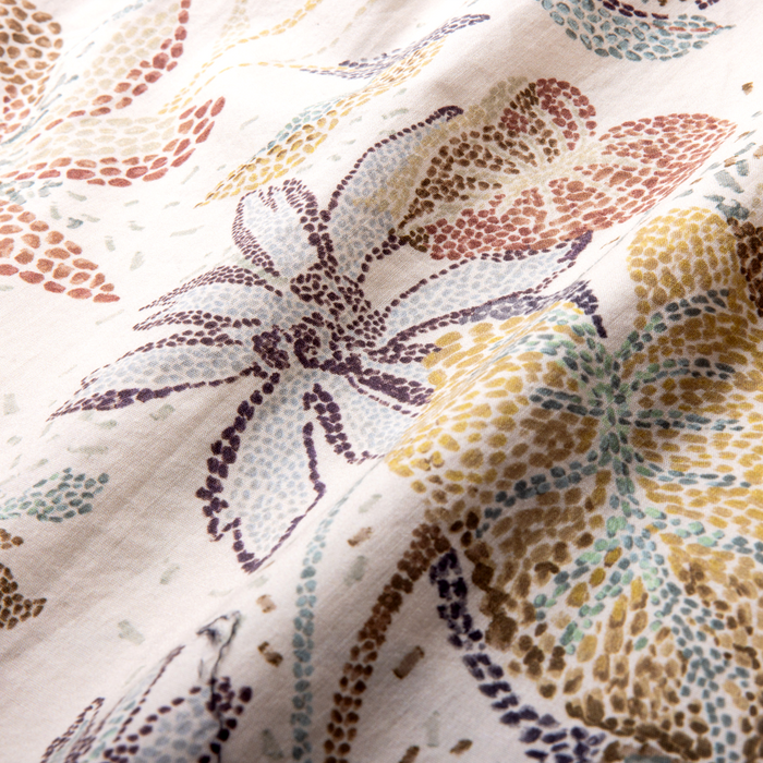 Ivory linen button-up shirt with multicolored botanical leaf print in purple, rust, yellow, and green, close-up detail view