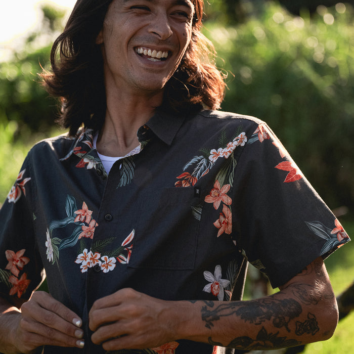 Smiling man wearing a Roark Journey Short Sleeve Button Up Shirt, showcasing collar and button details, perfect for adventure and travel.