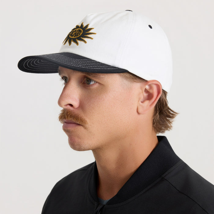 White and black Journey snapback hat with gold sun embroidery, worn by man in side profile view