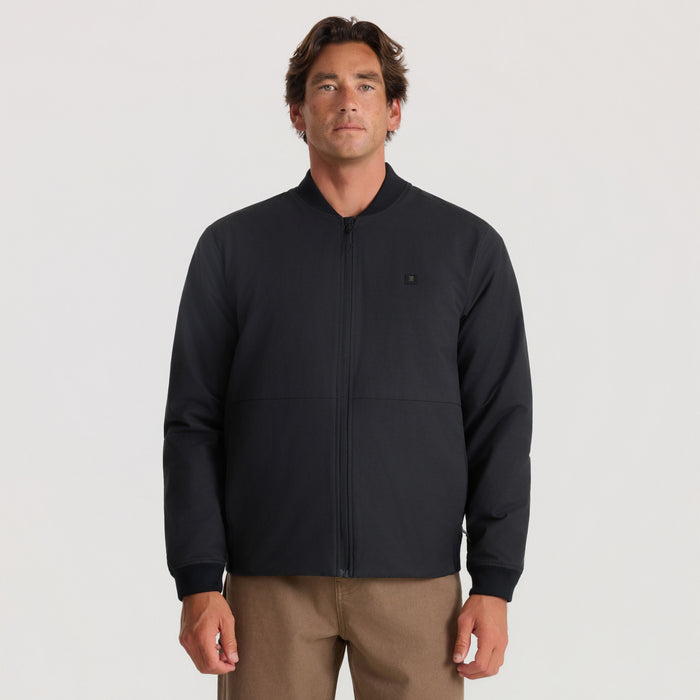Black Layover Bomber Jacket worn by man with tan pants against neutral background
