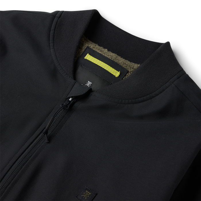 Black Layover Bomber Jacket detail showing ribbed collar, yellow brand label, and front zip closure on flat lay
